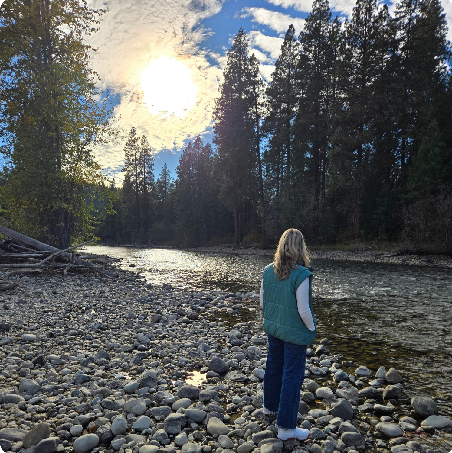 Sommer Seitz beside a sunlit forest river